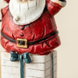 A Santa Christmas ornament close-up shows textured red resin, a white beard, black belt, gold buckle, and white gift with green ribbon.