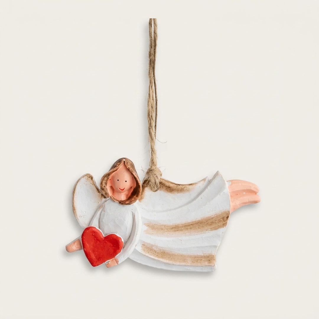 Resin Christmas ornament depicting a flying white angel with gold stripes and a red heart hangs against an off-white background.