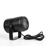 Black Christmas light projector with a U-shaped stand and coiled attached cable sits against a plain white background.