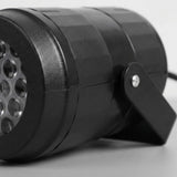 Black Christmas light projector appears close up against white, showing textured casing, partial circular lenses, and a stand with a silver screw.