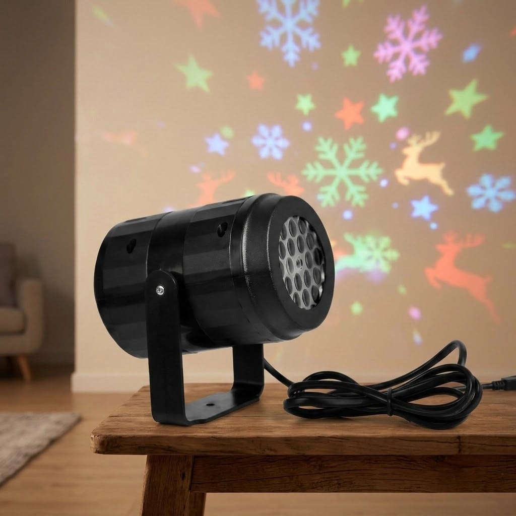 Black Christmas light projector rests on a wooden table beside coiled cable, with colorful snowflakes, stars, and reindeer projected onto the wall.