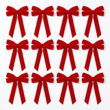 Twelve red velvet Christmas bows with long tails arranged in three rows of four on a plain white background.