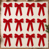 Twelve red velvet Christmas bows arranged in neat rows on cream paper over a wooden tabletop with evergreen sprigs and pinecones.