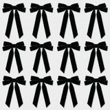 Twelve black velvet Christmas bows with long angled tails are arranged in three rows of four on a light gray background.