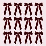 Twelve burgundy velvet Christmas bows with long angled tails are arranged in three rows of four on a pale pink background.