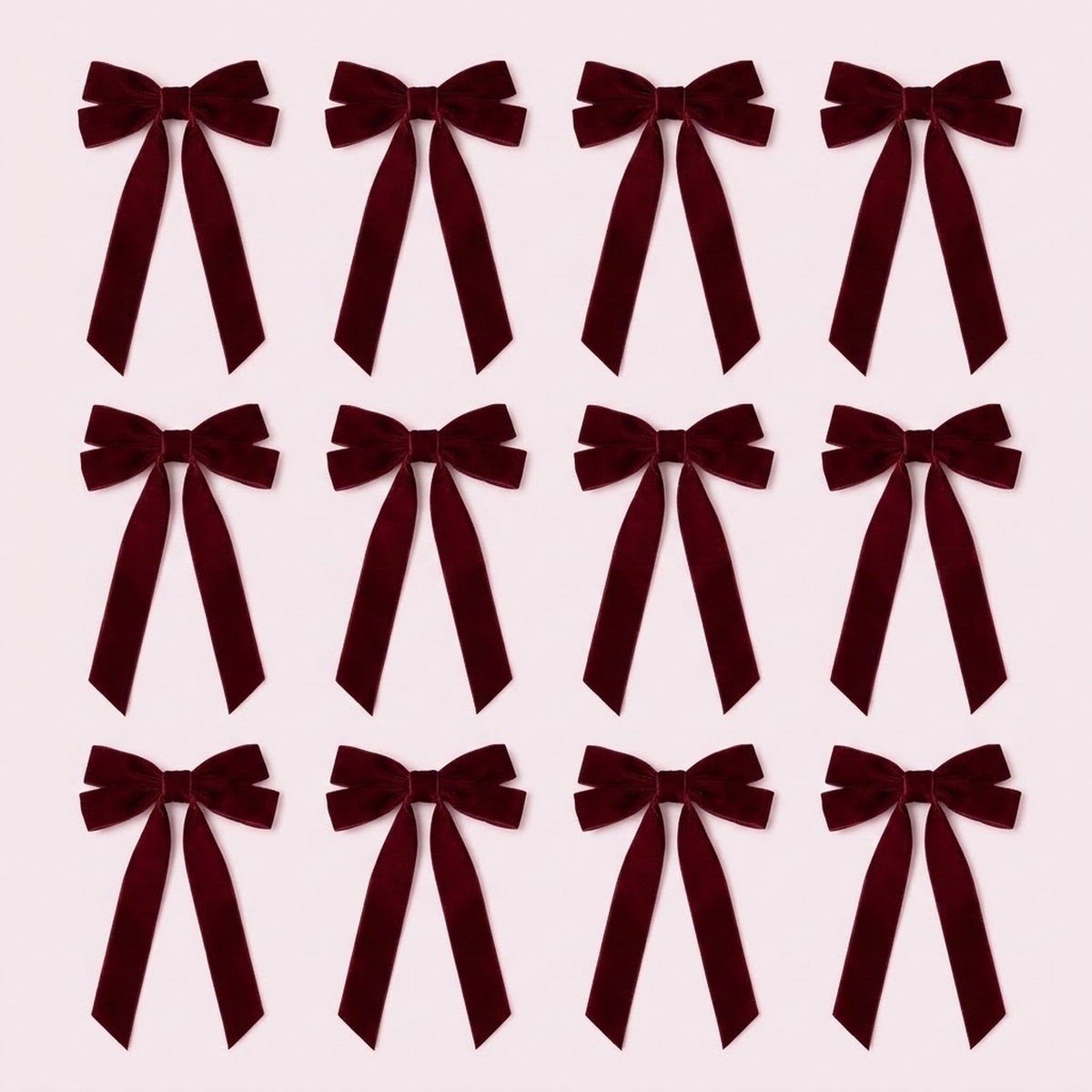 Twelve burgundy velvet Christmas bows with long angled tails are arranged in three rows of four on a pale pink background.