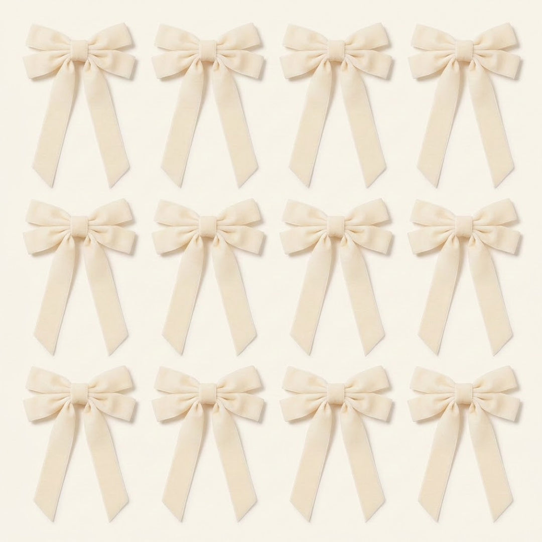 Twelve ivory velvet Christmas bows with long angled tails are arranged in three rows of four on a cream background.