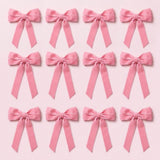 Twelve pink velvet Christmas bows with long angled tails are arranged in three rows of four on a pale pink background.