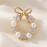 A gold-tone bow stud earring with white pearl-like beads and clear faceted stones rests on folded cream satin.