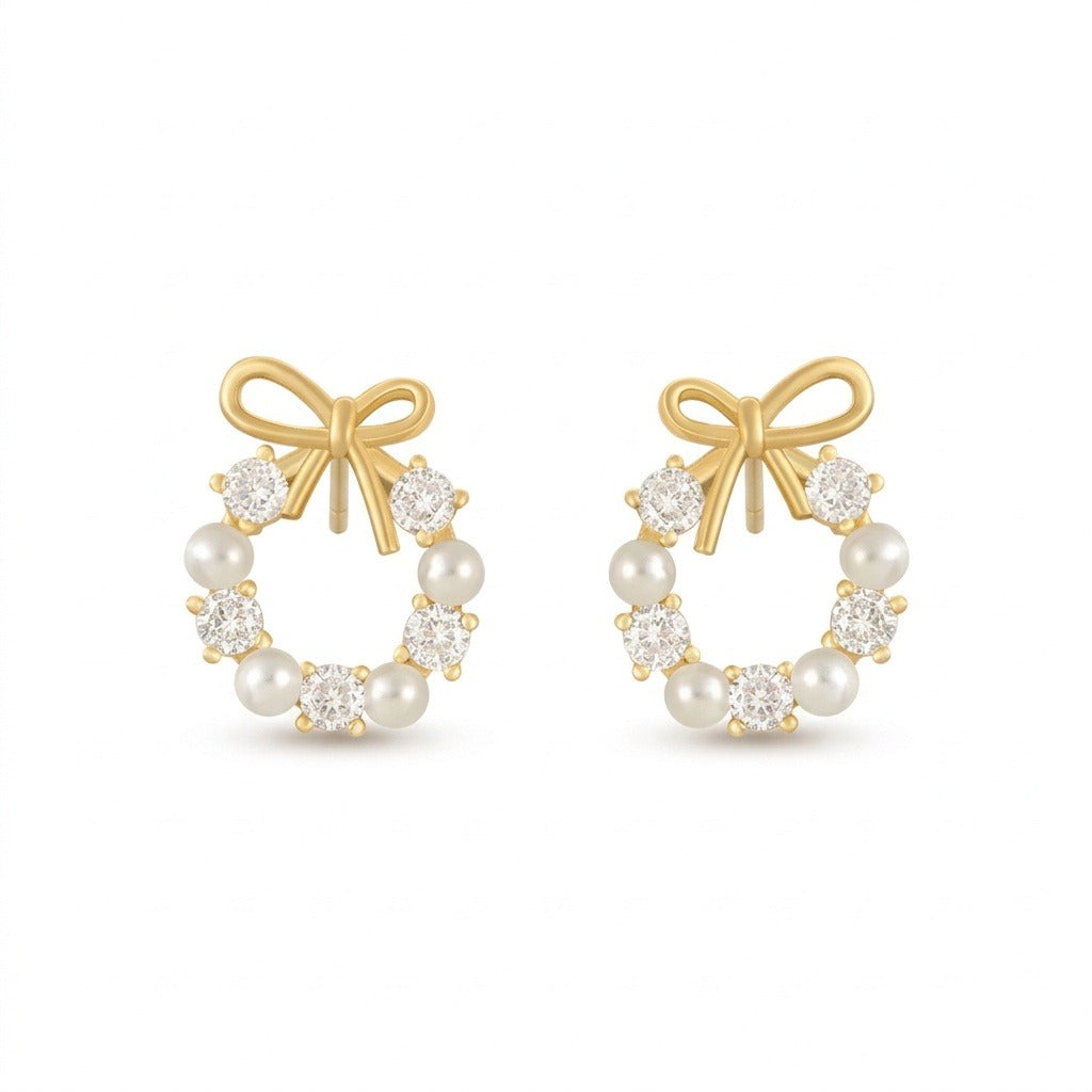 Two matching gold-tone bow stud earrings with white pearl-like beads and clear faceted stones stand side by side against white.