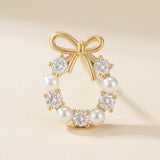 A gold-tone bow stud earring with white pearl-like beads and clear faceted stones stands on a cream surface, casting a shadow.