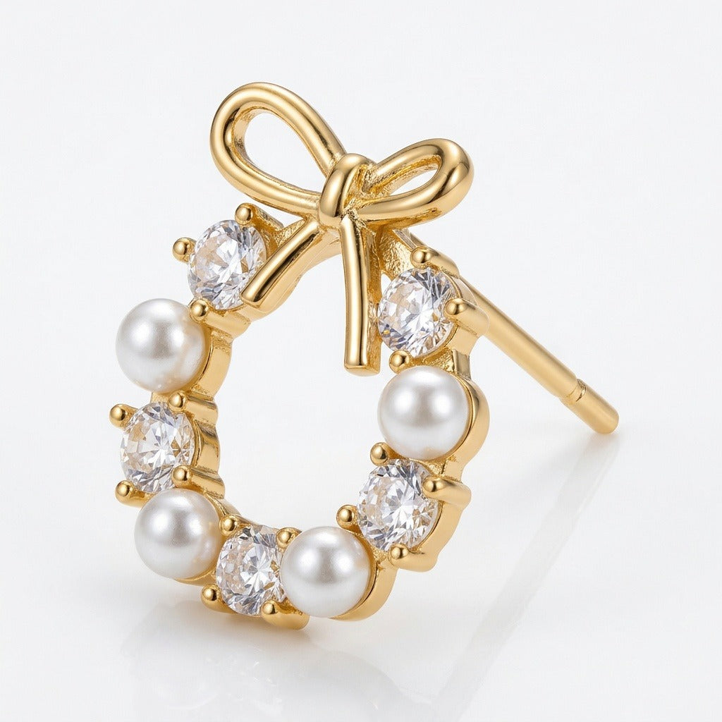 Gold-tone wreath-shaped stud earring with a bow, white pearl-like beads, and clear faceted stones on a white background.