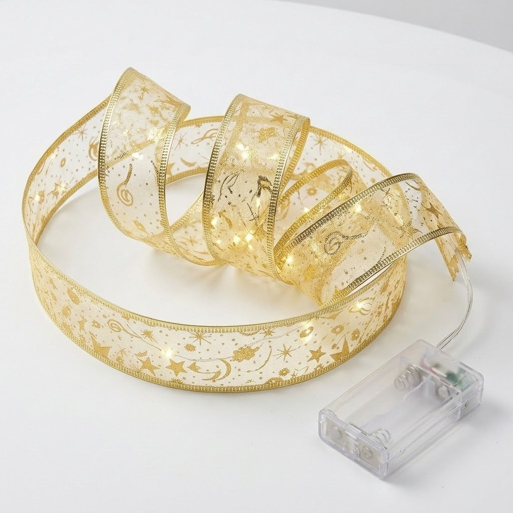 Gold patterned ribbon light string forms loose glowing loops beside an empty clear battery box on a white surface.