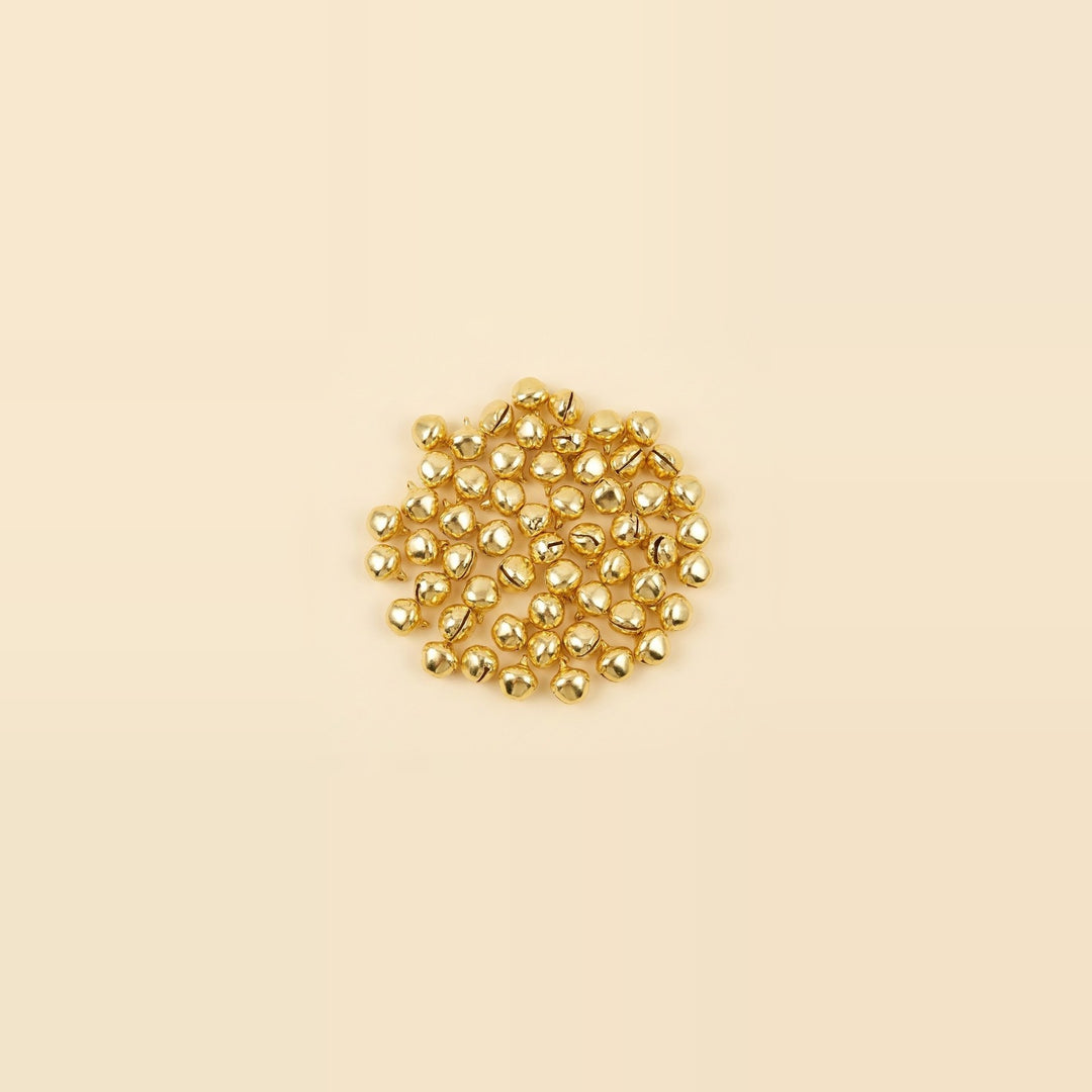 A small central cluster of shiny gold jingle bells sits against a spacious pale cream background.