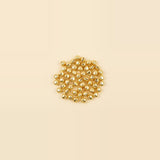 A small central cluster of shiny gold jingle bells sits against a spacious pale cream background.