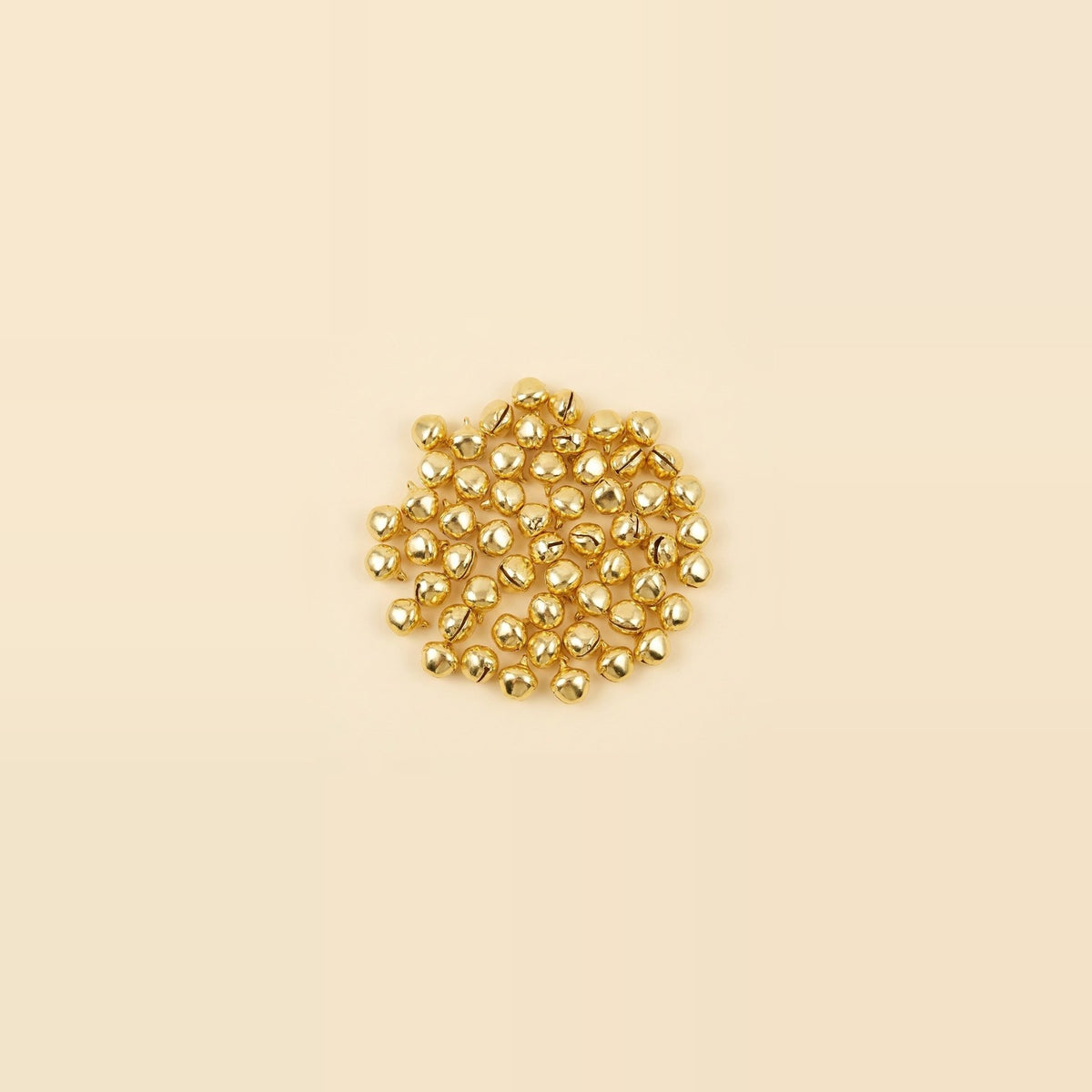 A small central cluster of shiny gold jingle bells sits against a spacious pale cream background.