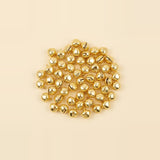 Reflective gold jingle bells lie in a loose rounded arrangement on a plain pale cream surface.