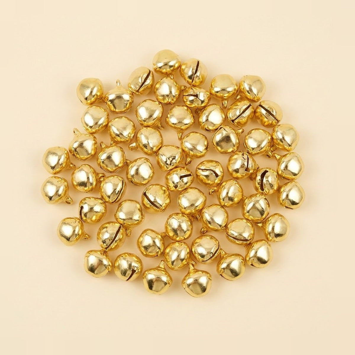 Shiny gold jingle bells with hanging loops form a loose circular cluster on a pale cream background.