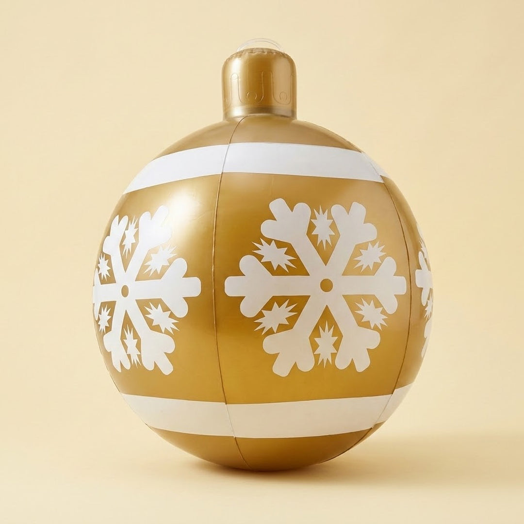 A gold inflatable Christmas ornament with white snowflakes, horizontal bands, and a gold cap stands against a pale yellow background.
