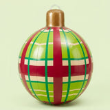 An inflatable Christmas ornament with red, green, and cream plaid stripes and a gold cap stands against a pale green background.