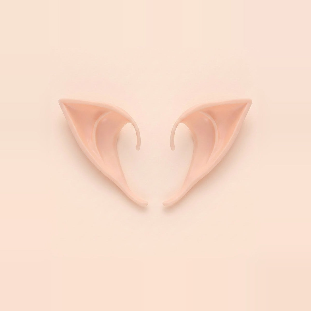 Light peach latex elf costume ears with curved hooks lying side by side on a pale peach background, 3.94 in (10 cm) pair.