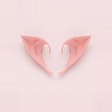 Pink latex elf costume ears with curved hooks lying side by side on a pale pink background, 3.94 in (10 cm) pair.