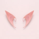 Pink latex elf costume ears with curved hooks lying side by side on a pale pink background, 4.72 in (12 cm) pair.