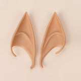Warm tan latex elf costume ears with curved hooks lying side by side on a cream background, 4.72 in (12 cm) pair.