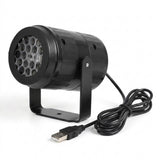 A black snowflake projector faces left on a U-shaped stand with its coiled USB cable against a white background.