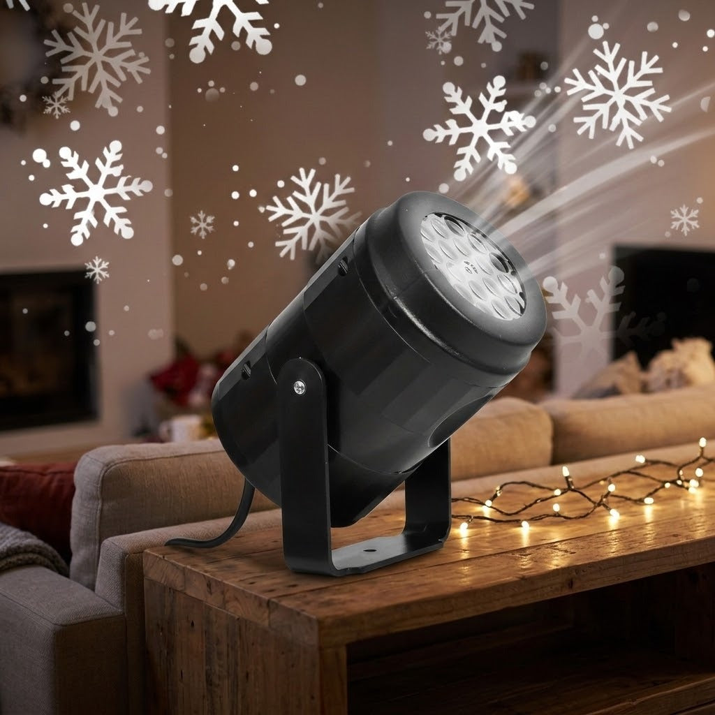 Black projector light on a wooden console casts white snowflake patterns across a living room, with warm string lights nearby.