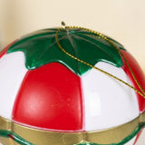 Close-up of the balloon Christmas decorative light shows red and white panels, a green top, gold trim, and hanging cord against cream.