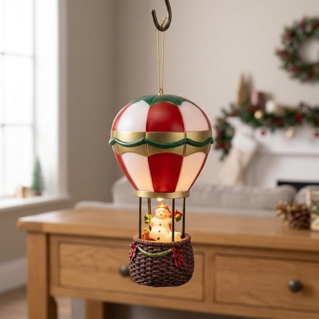 Red and white snowman hot air balloon Christmas decorative light hangs above a wooden console near a garland-decorated fireplace.