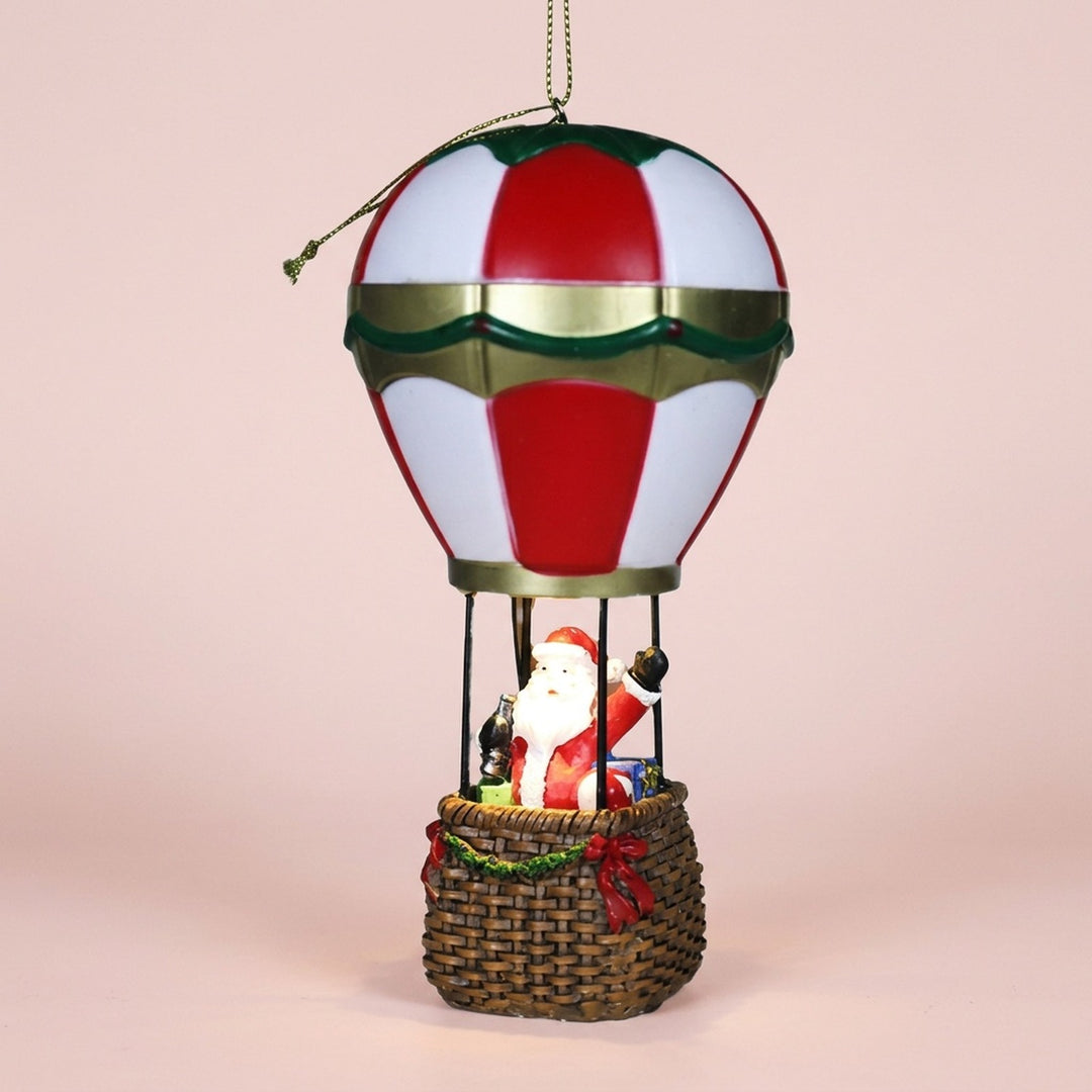 Santa hot air balloon Christmas decorative light features red and white panels, green and gold trim, and a brown basket against pale pink.