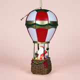 Santa hot air balloon Christmas decorative light features red and white panels, green and gold trim, and a brown basket against pale pink.