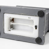 The Christmas decorative light’s gray underside shows an empty white battery compartment, a black sliding switch, and round black feet against white.