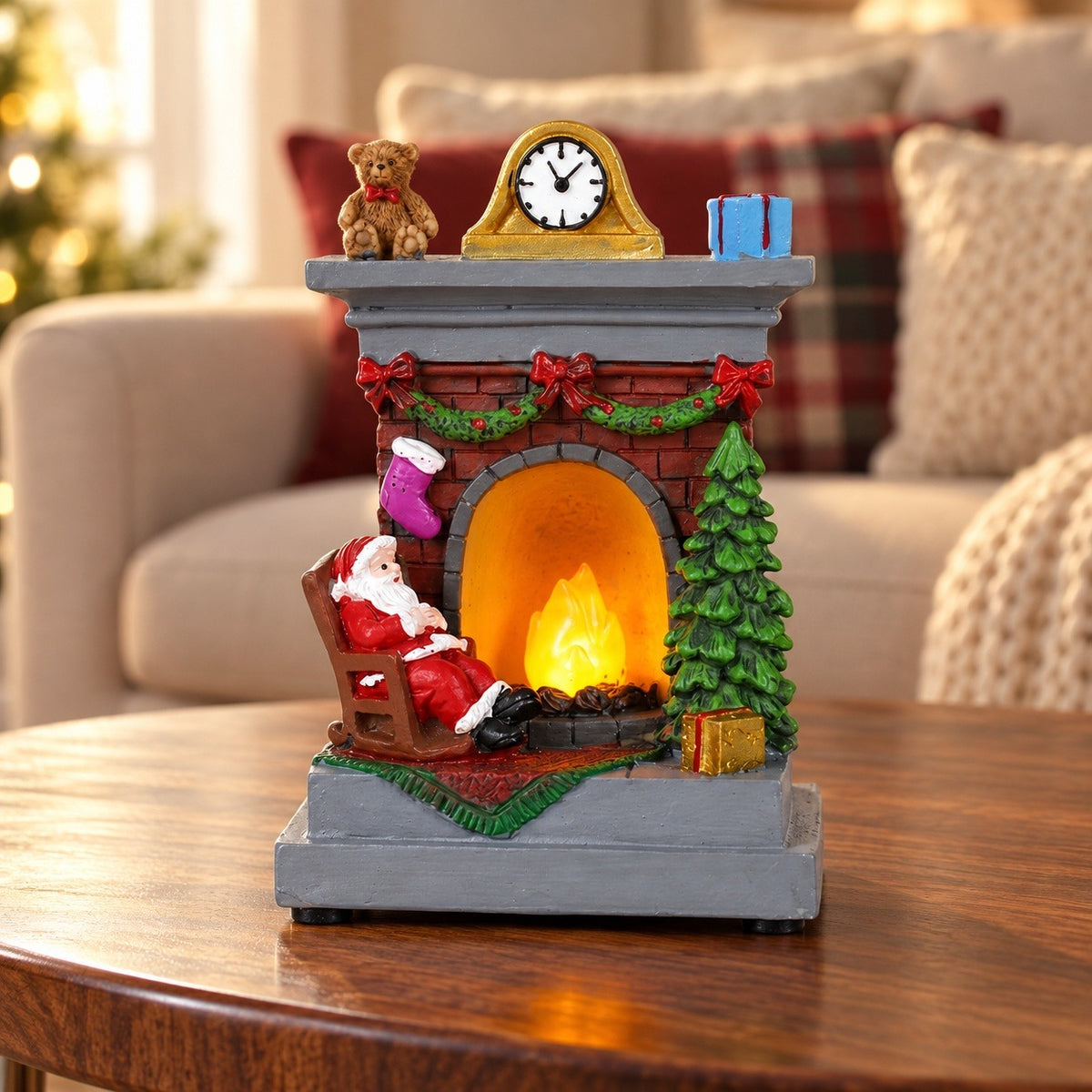 Glowing Santa fireplace Christmas decorative light with a green tree and gray mantel stands on a wooden table before a cream sofa.