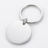 Silver keychain with a plain circular pendant reverse, small connector ring, and round split ring lies diagonally on a white background.