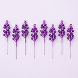 Eight purple glitter berry picks with exposed gray stems alternate heights in a row on a pale lavender background.