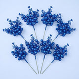 Eight royal blue glitter berry picks with slender green stems form two fans on a pale blue background.