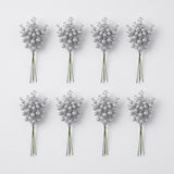 Eight bunches of silver glitter berry picks with green stems form two rows of four on a pale gray background.