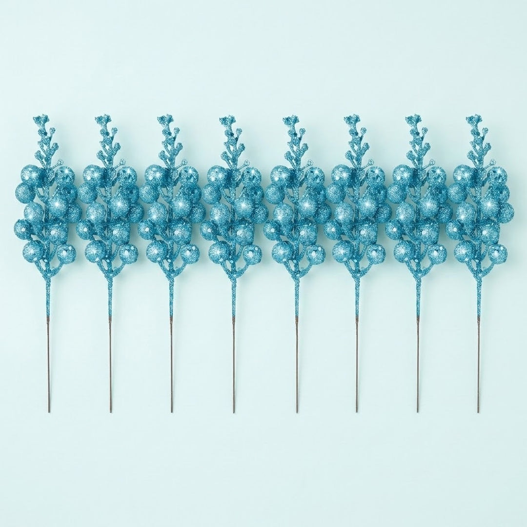 Eight turquoise blue glitter berry picks with long slender stems lie side by side on a pale blue background.