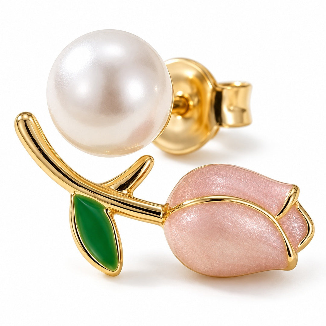A gold-tone tulip stud earring rests on white with a pink bud, green leaf, white pearl-like bead, and visible push-back.