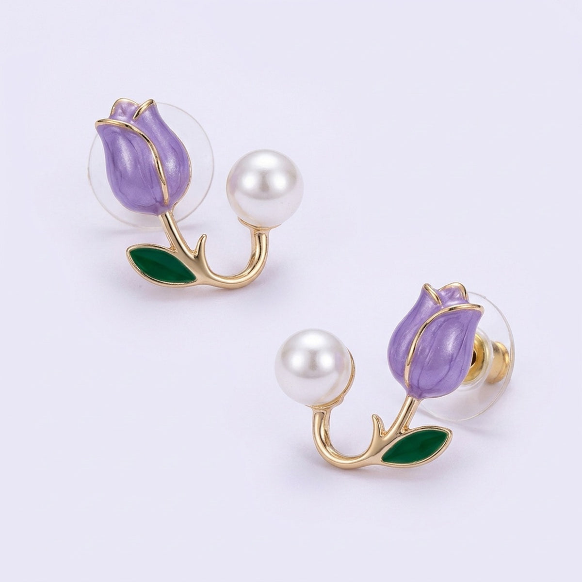 Lavender tulip stud earrings with gold-tone stems, green leaves, white pearl-like beads, and clear circular backs on a pale lavender background.
