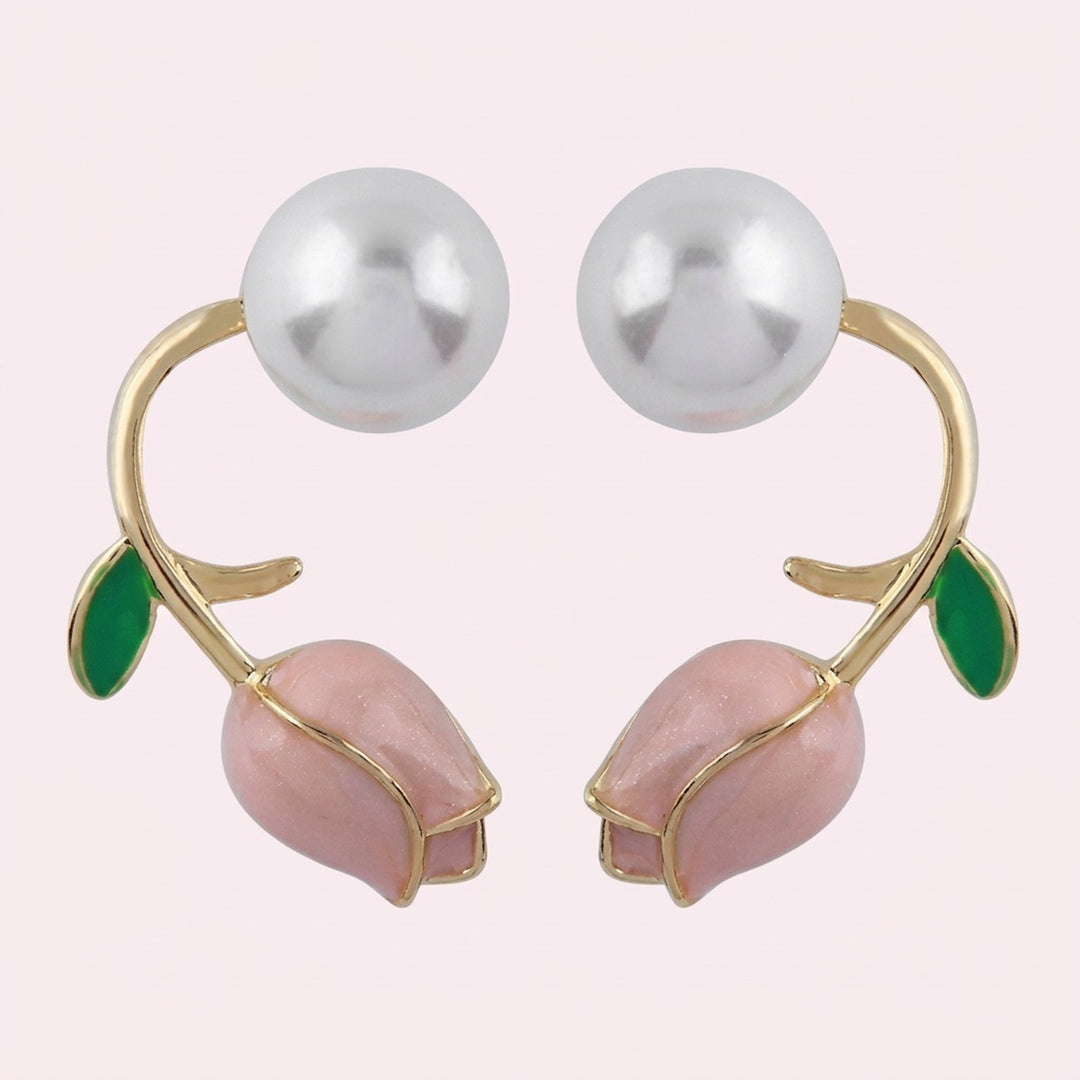 Pale pink tulip bud stud earrings with curved gold-tone stems, green leaves, and large white pearl-like beads on a pale background.