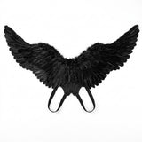 Connected black feather costume wings with two looped shoulder straps are spread against a plain white background.