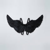 Black feather costume wings spread wide with raised tips and matching shoulder straps against a light gray background.