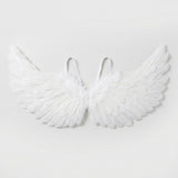 White feather costume wings have layered feathers, raised tips, and two visible shoulder loops against a pale gray background.