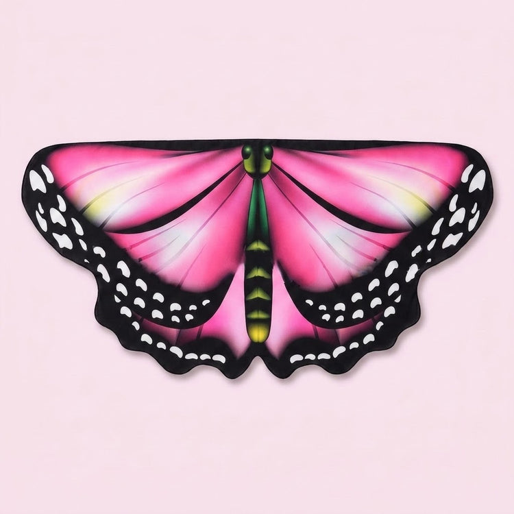 Bright pink butterfly wing cape shawl with black spotted edges and a green body detail, laid flat on a pale pink background.