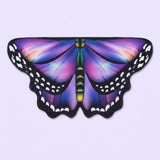 Purple and blue butterfly wing cape with soft pink highlights, black spotted borders, and a green body, on a lilac background.