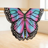 Pink and turquoise chiffon butterfly cape hangs over a wooden ballet barre in a bright room with pale walls and flooring.